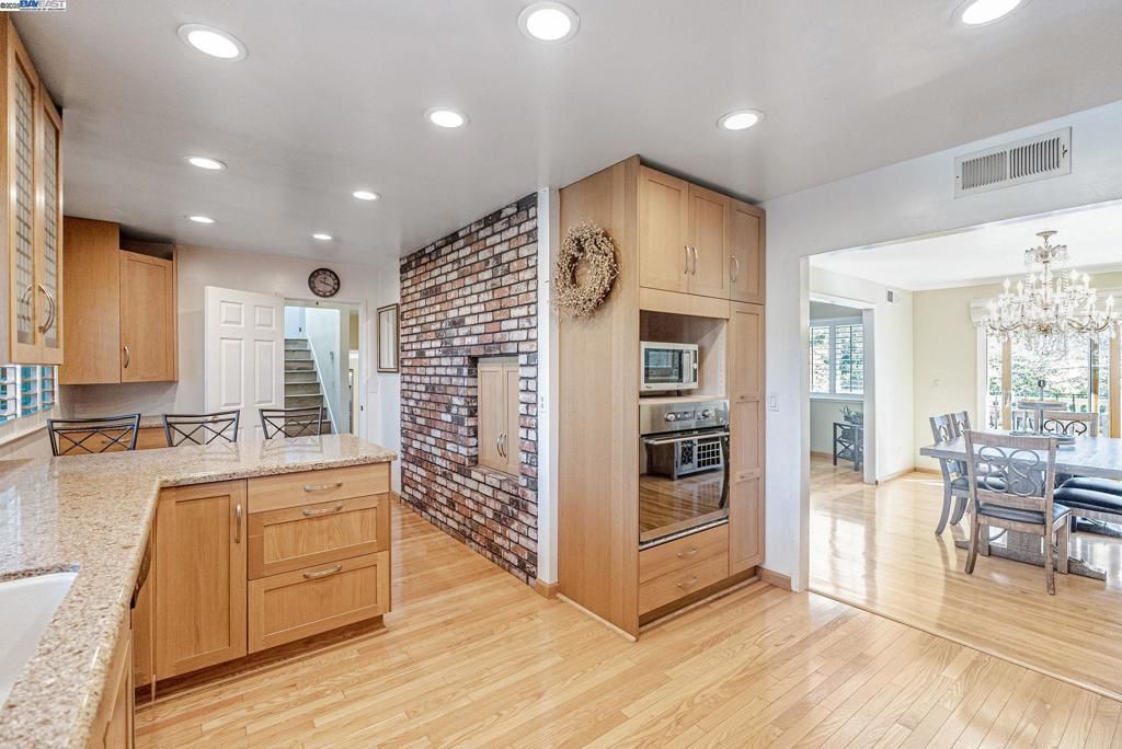 Chandelier, Dining room, Interior, Kitchen, Recessed Lighting, Stainless Steel Appliances, Stone Walls, Wood Texture Flooring