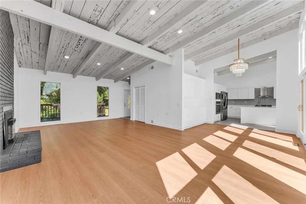 Chandelier, Empty room, Fireplace, Interior, Kitchen, Recessed Lighting, Stainless Steel Appliances, Wooden Ceilings, Wood Texture Flooring
