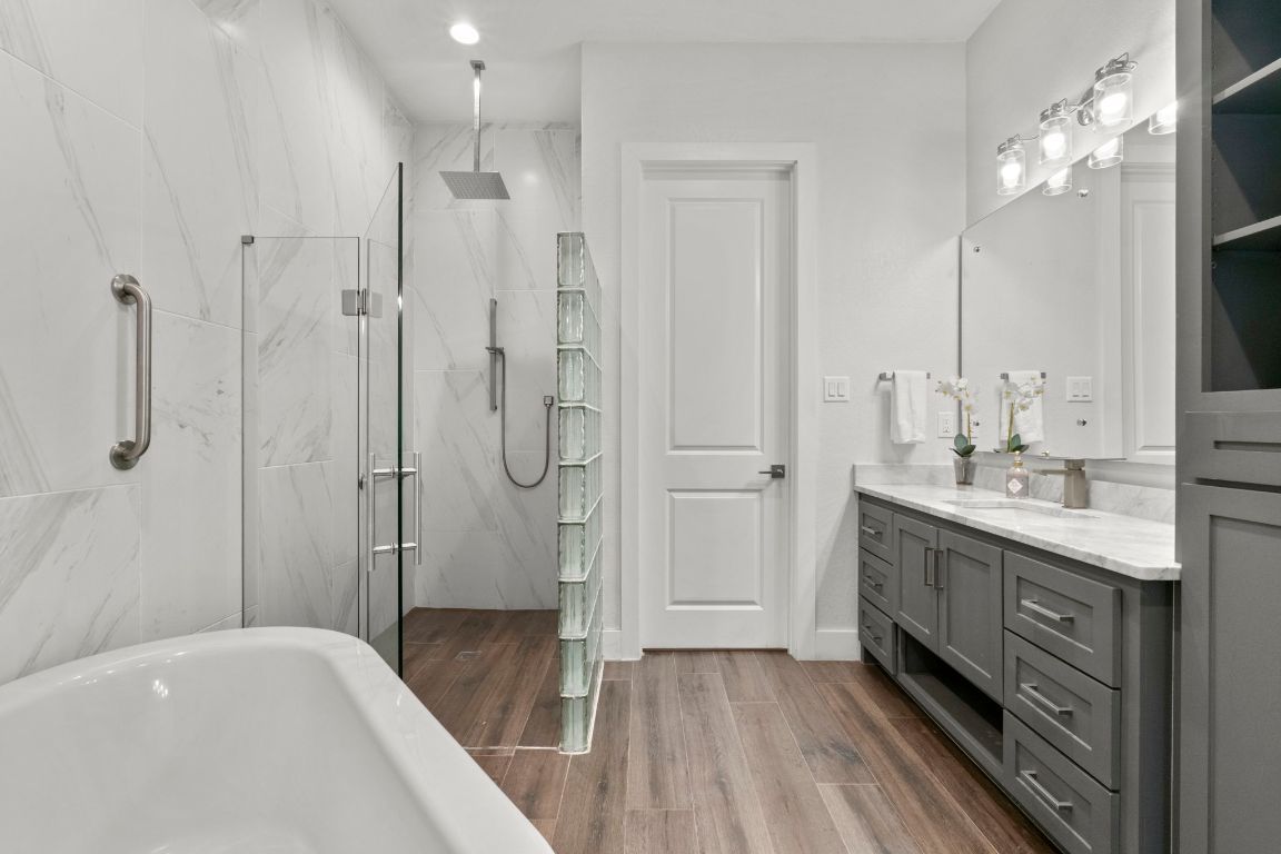 Bathroom, Dual Sink Vanities, Free Standing Baths, Glass Shower, Interior, Marble Walls, Recessed Lighting, Wood Texture Flooring