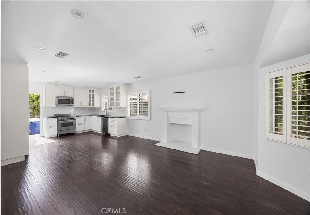 Empty room, Fireplace, Interior, Kitchen, Recessed Lighting, Stainless Steel Appliances, Wood Texture Flooring