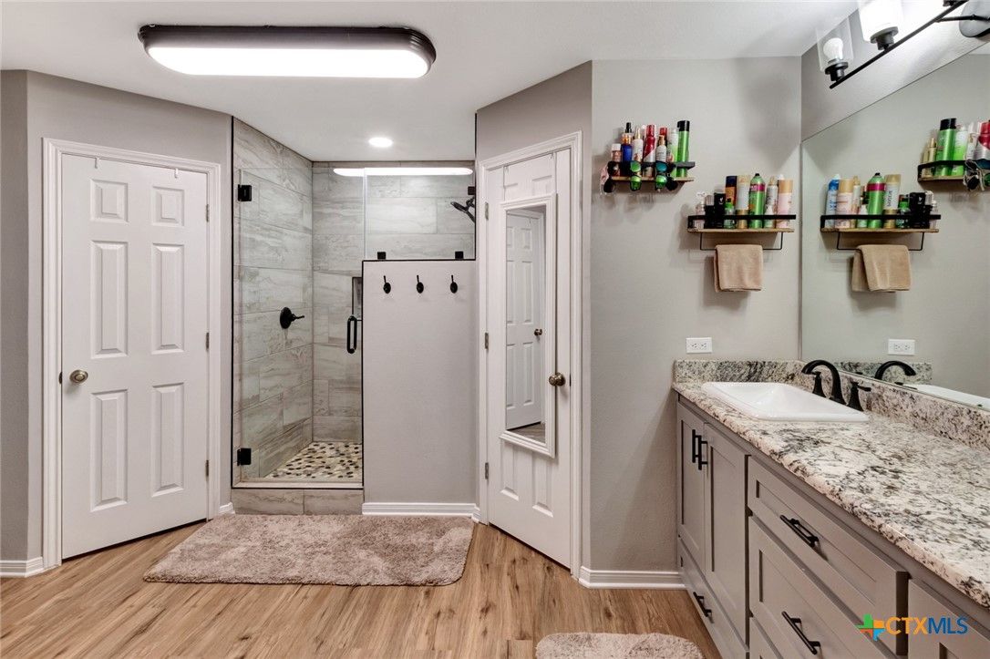 Bathroom, Dual Sink Vanities, Glass Shower, Interior, Marble Walls, Recessed Lighting, Wood Texture Flooring