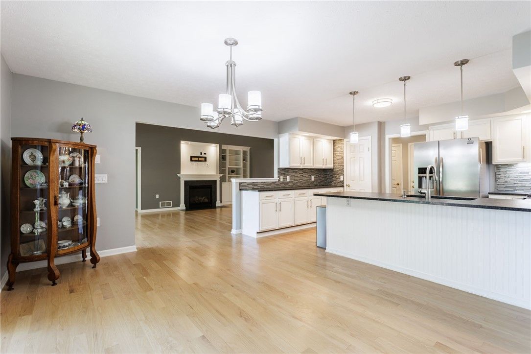 Chandelier, Empty room, Fireplace, Interior, Kitchen, Pendant Lights, Stainless Steel Appliances, Wood Texture Flooring