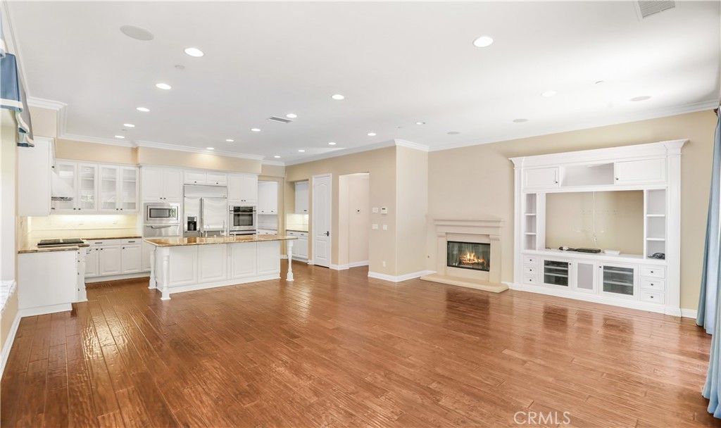 Empty room, Fireplace, Interior, Kitchen, Recessed Lighting, Stainless Steel Appliances, Wood Texture Flooring