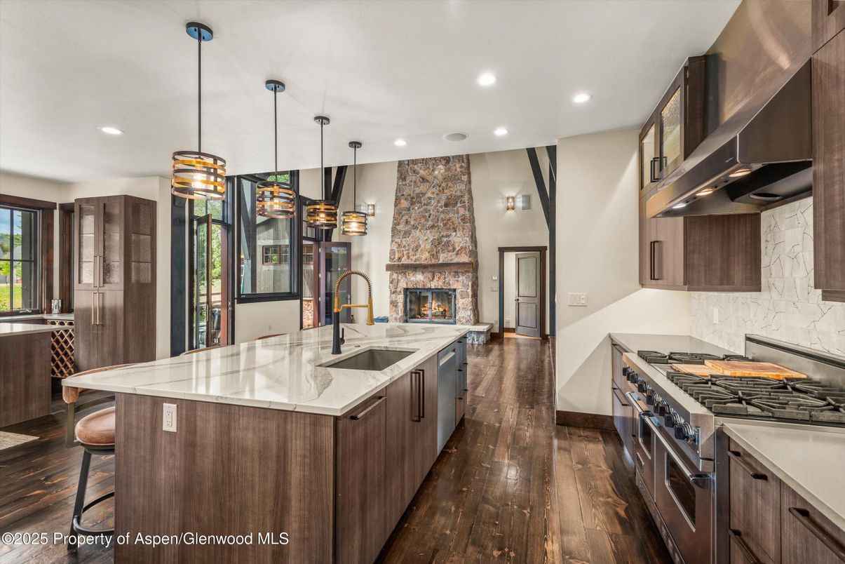 Fireplace, Interior, Kitchen, Pendant Lights, Recessed Lighting, Stainless Steel Appliances, Stone Walls, Wood Texture Flooring