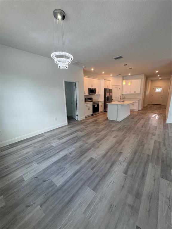 Chandelier, Empty room, Interior, Kitchen, Pendant Lights, Recessed Lighting, Stainless Steel Appliances, Wood Texture Flooring