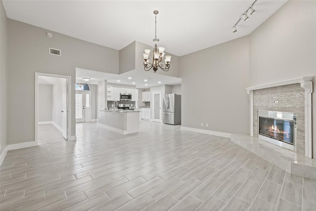 Chandelier, Empty room, Fireplace, Interior, Kitchen, Recessed Lighting, Stainless Steel Appliances, Wood Texture Flooring