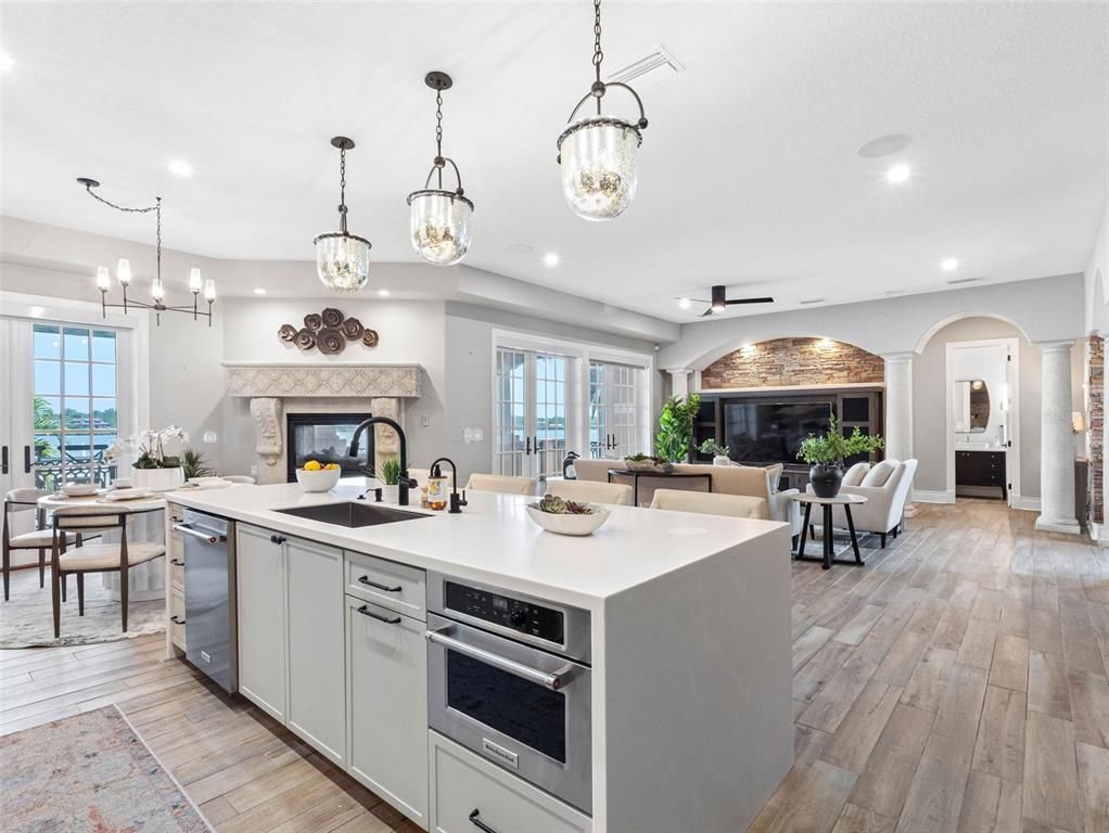 Chandelier, Dining room, Fireplace, Interior, Kitchen, Living room, Pendant Lights, Recessed Lighting, Stainless Steel Appliances, Stone Walls, Wood Texture Flooring