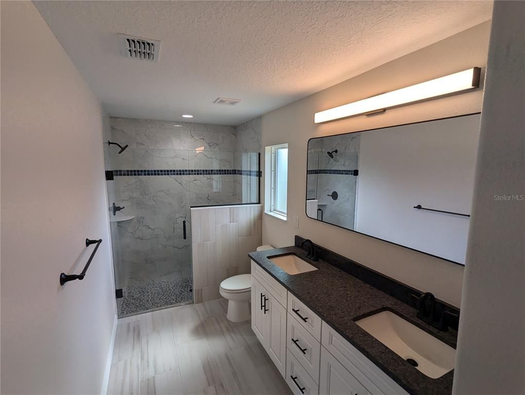Bathroom, Dual Sink Vanities, Glass Shower, Interior, Marble Walls, Recessed Lighting, Wood Texture Flooring