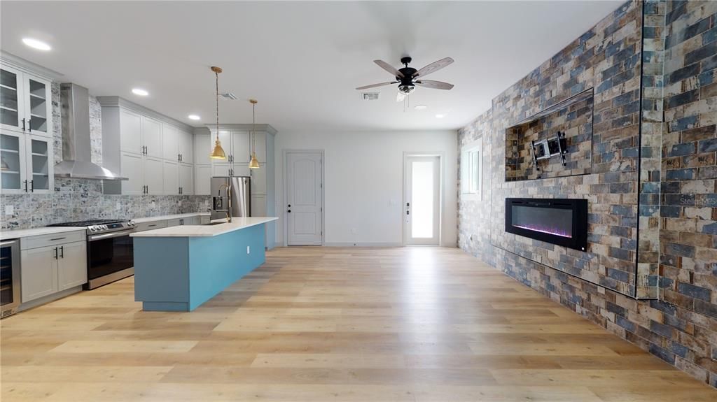 Empty room, Fireplace, Interior, Kitchen, Pendant Lights, Recessed Lighting, Stainless Steel Appliances, Stone Walls, Wood Texture Flooring