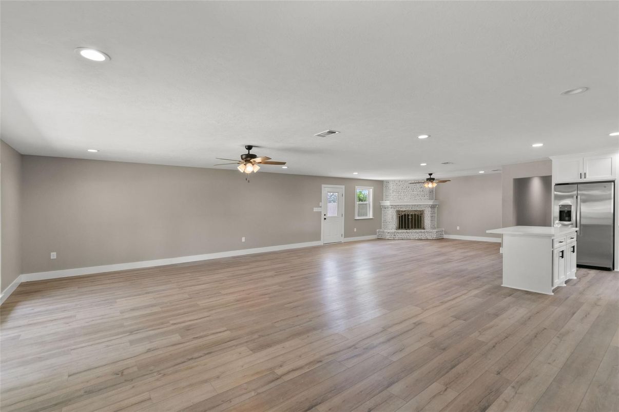 Empty room, Fireplace, Interior, Kitchen, Recessed Lighting, Stainless Steel Appliances, Wood Texture Flooring