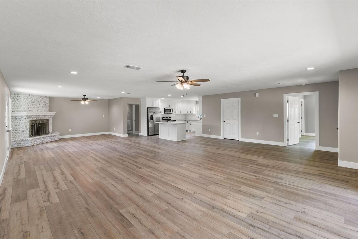 Empty room, Fireplace, Interior, Kitchen, Recessed Lighting, Stainless Steel Appliances, Wood Texture Flooring