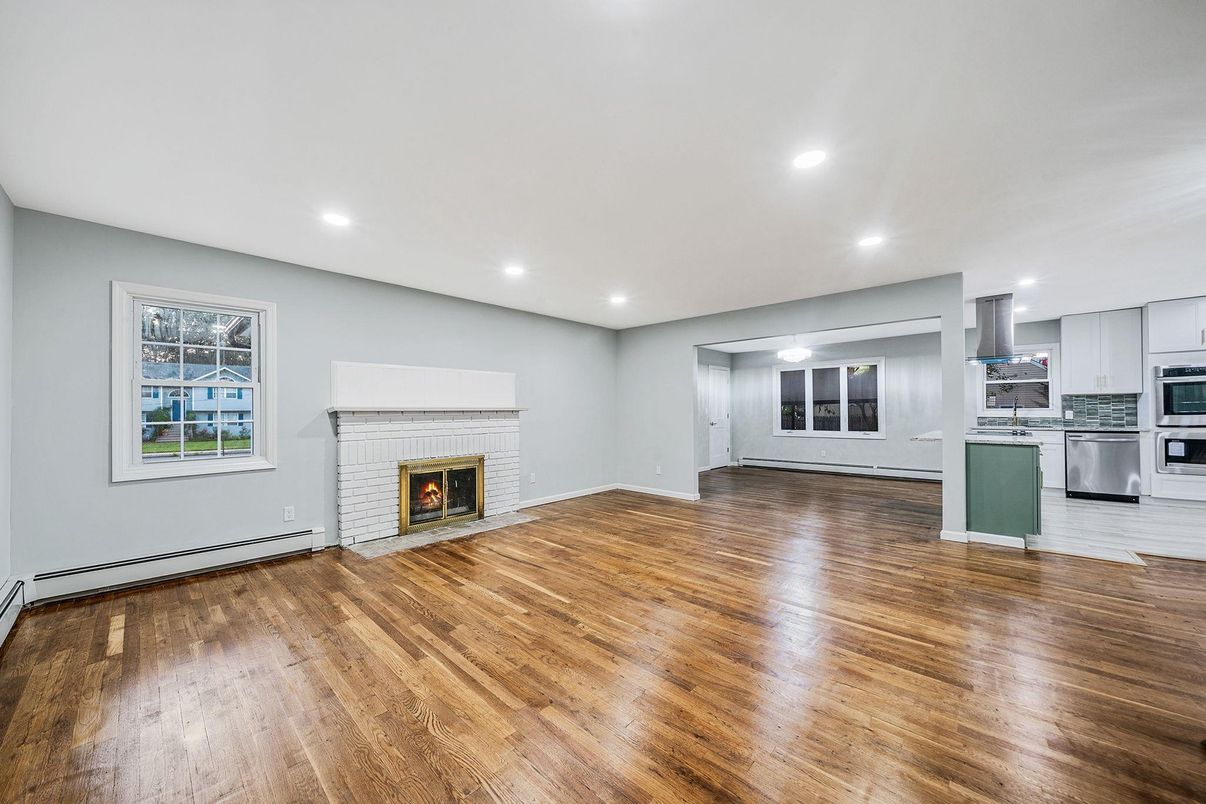 Empty room, Fireplace, Interior, Kitchen, Recessed Lighting, Stainless Steel Appliances, Wood Texture Flooring