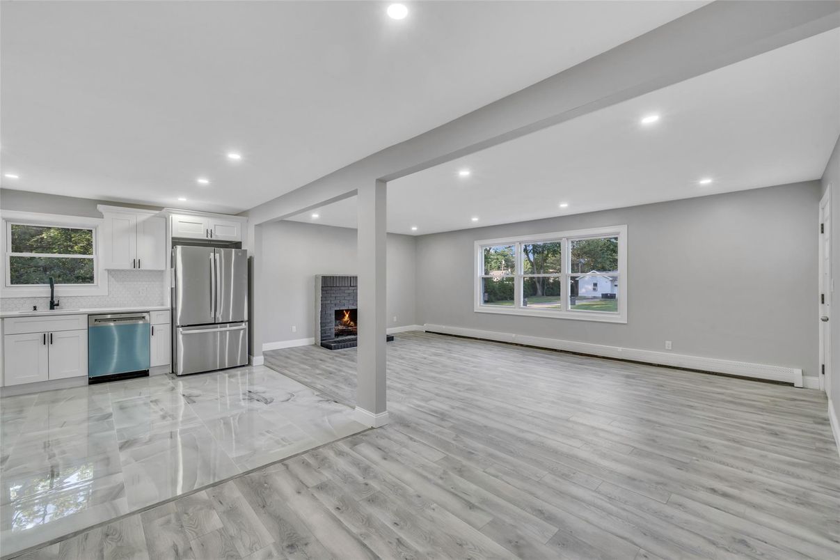 Empty room, Fireplace, Interior, Kitchen, Recessed Lighting, Stainless Steel Appliances, Wood Texture Flooring