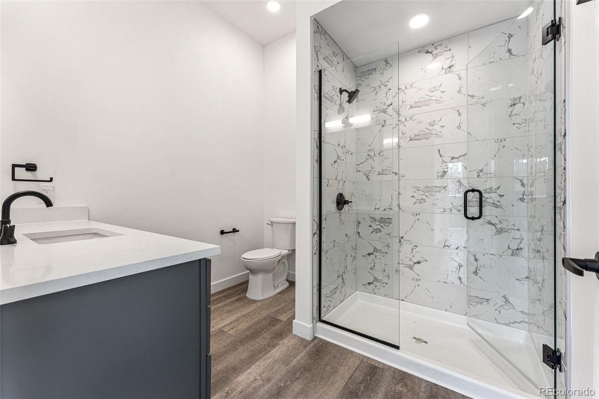 Bathroom, Dual Sink Vanities, Glass Shower, Interior, Marble Walls, Recessed Lighting, Wood Texture Flooring