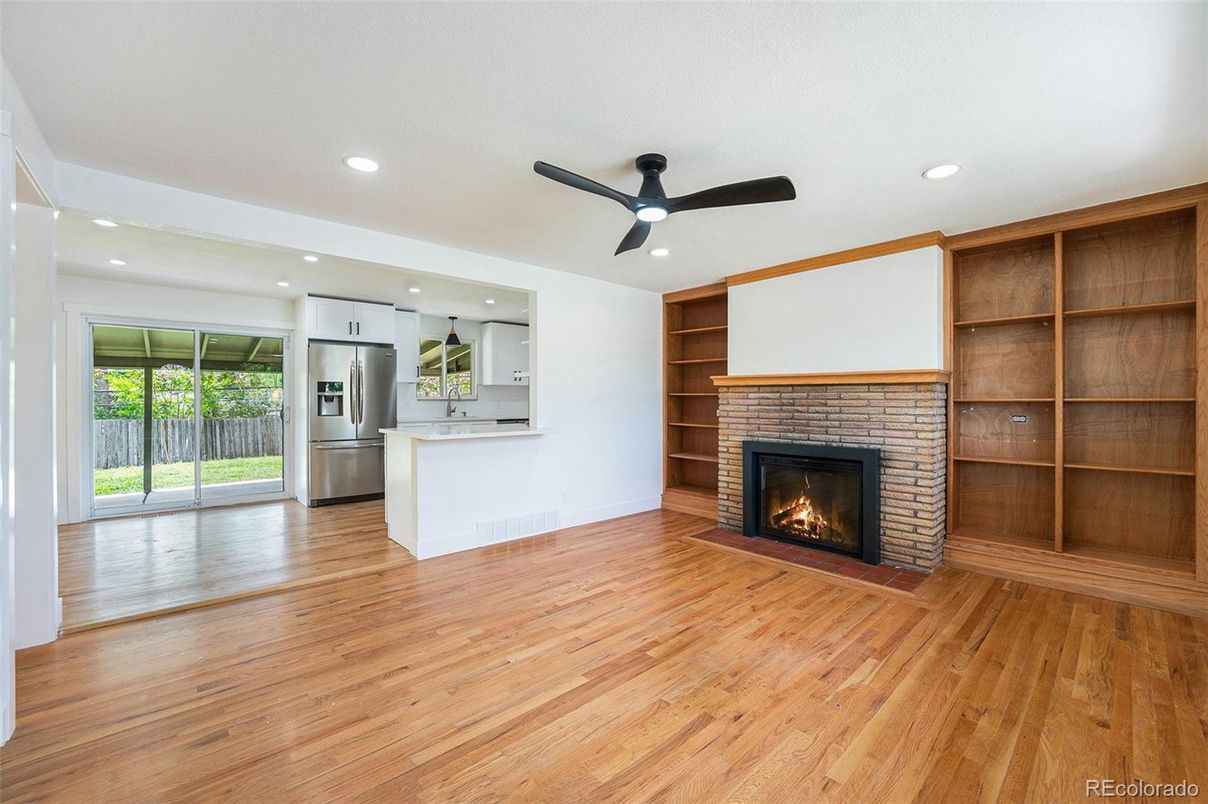 Empty room, Fireplace, Interior, Kitchen, Recessed Lighting, Stainless Steel Appliances, Wood Texture Flooring