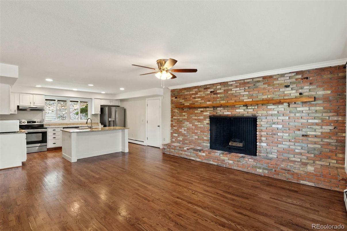 Empty room, Fireplace, Interior, Kitchen, Recessed Lighting, Stainless Steel Appliances, Stone Walls, Wood Texture Flooring