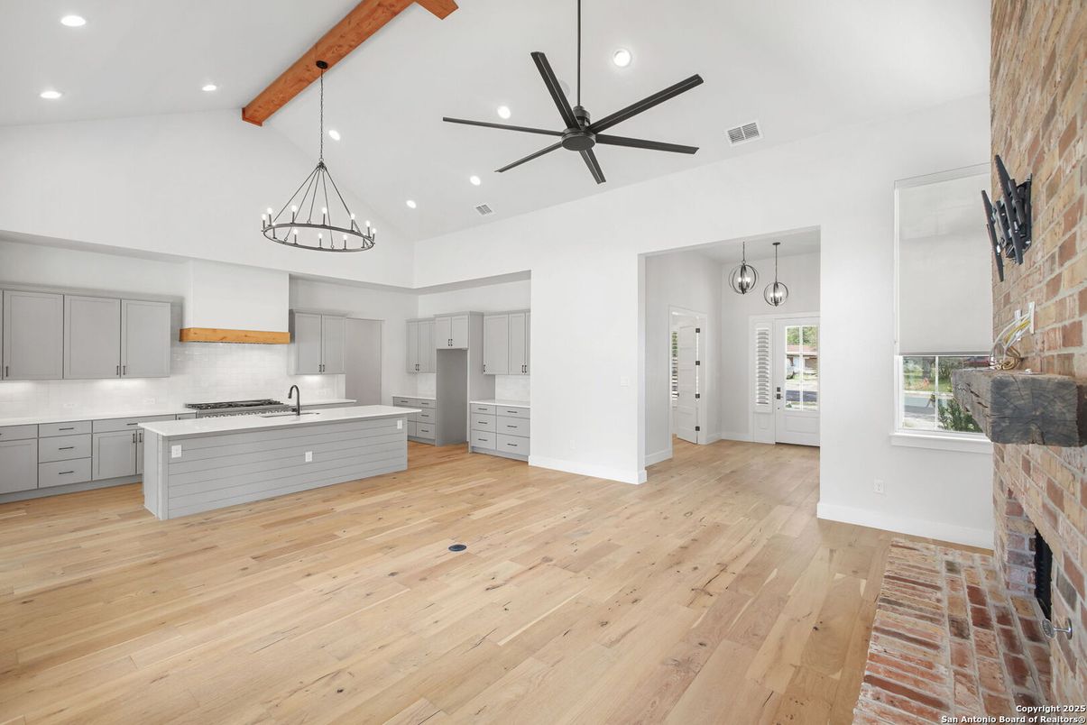 Chandelier, Empty room, Fireplace, Interior, Kitchen, Pendant Lights, Recessed Lighting, Stainless Steel Appliances, Stone Walls, Wooden Beams, Wood Texture Flooring
