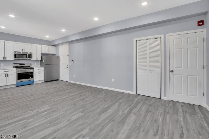 Empty room, Interior, Kitchen, Recessed Lighting, Stainless Steel Appliances, Wood Texture Flooring