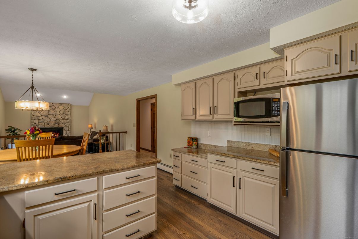 Dining room, Fireplace, Interior, Kitchen, Pendant Lights, Stainless Steel Appliances, Stone Walls, Wood Texture Flooring
