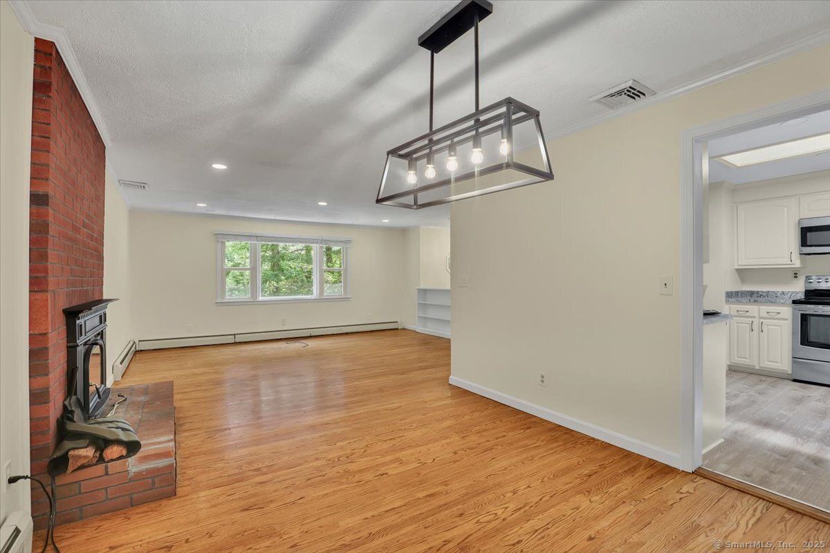Empty room, Fireplace, Interior, Kitchen, Pendant Lights, Recessed Lighting, Stainless Steel Appliances, Stone Walls, Wood Texture Flooring