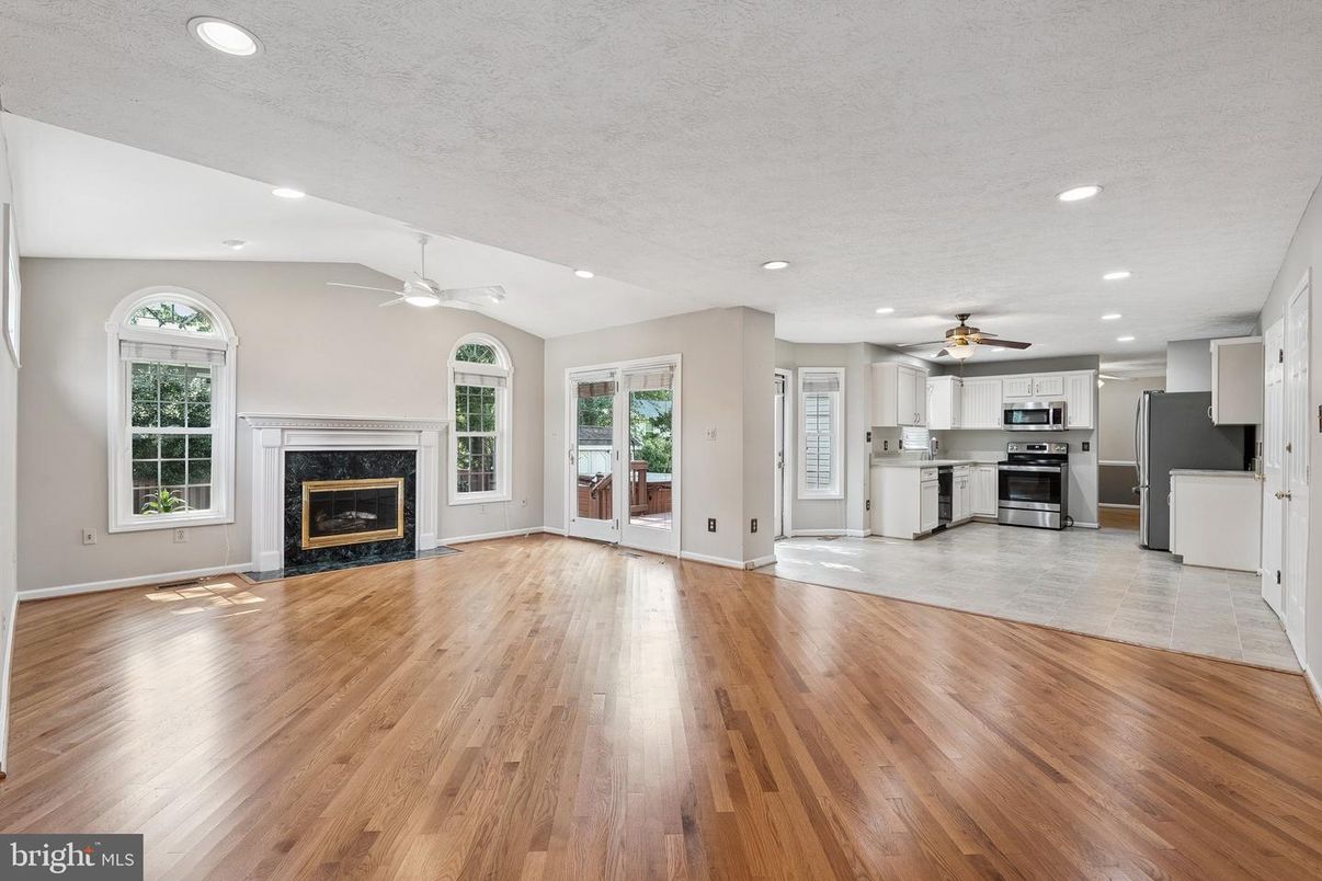 Empty room, Fireplace, Interior, Kitchen, Recessed Lighting, Stainless Steel Appliances, Wood Texture Flooring