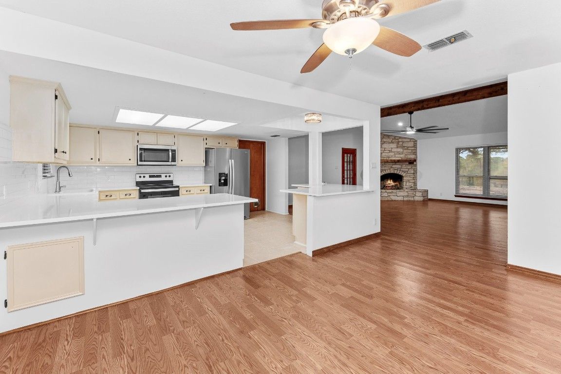 Empty room, Fireplace, Interior, Kitchen, Stainless Steel Appliances, Stone Walls, Wood Texture Flooring