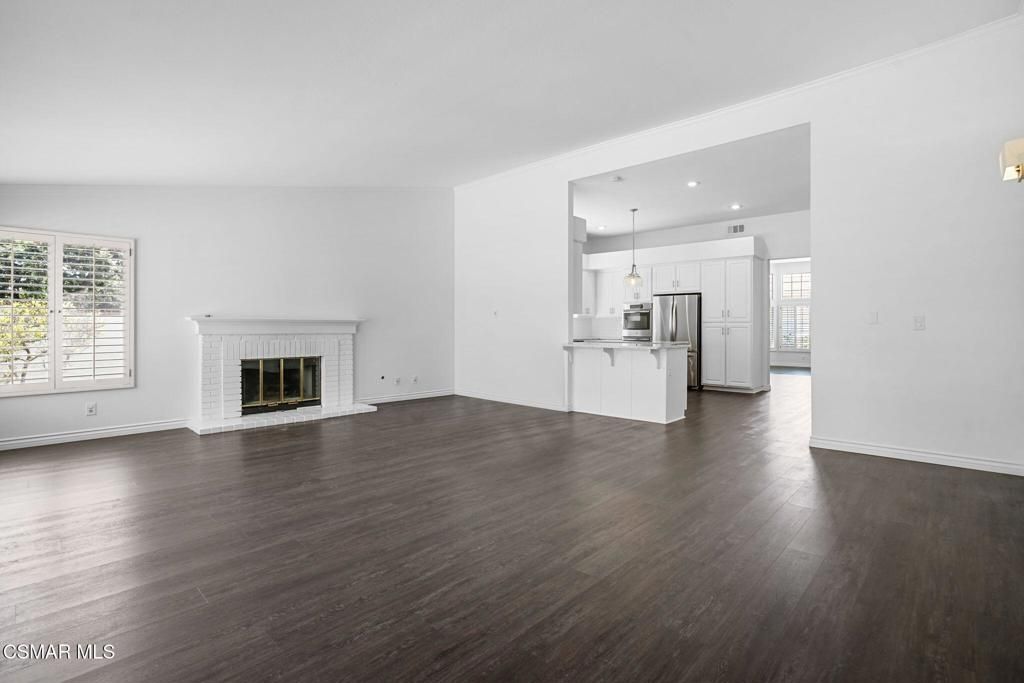 Empty room, Fireplace, Interior, Kitchen, Pendant Lights, Recessed Lighting, Stainless Steel Appliances, Wood Texture Flooring