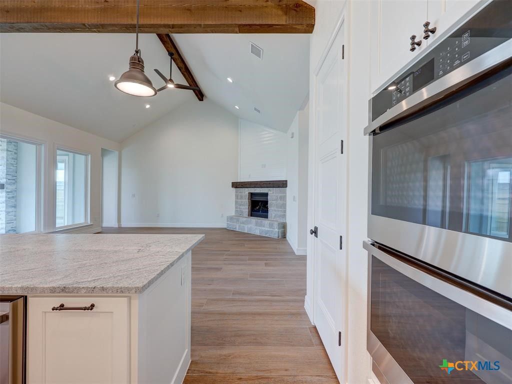 Empty room, Fireplace, Interior, Kitchen, Pendant Lights, Recessed Lighting, Stainless Steel Appliances, Wooden Beams, Wood Texture Flooring