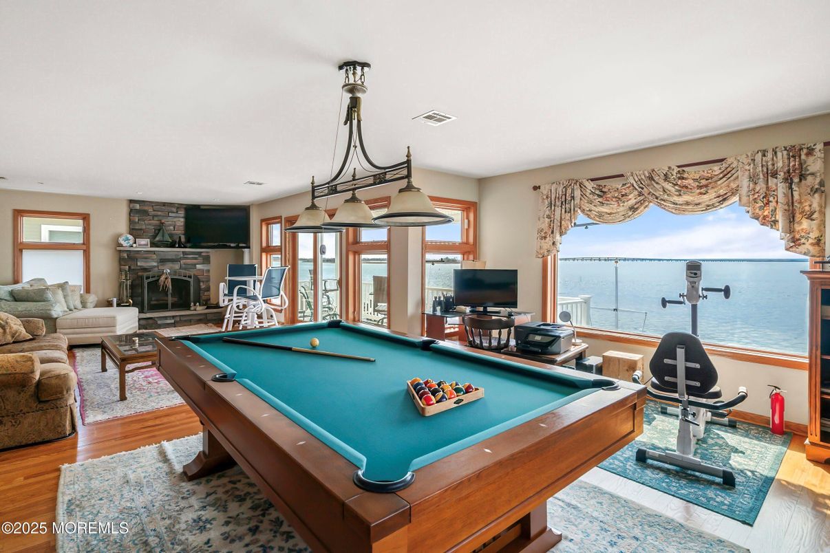 Billiard Table, Chandelier, Fireplace, Game Room, Interior, Living room, Stone Walls, Water, Wood Texture Flooring