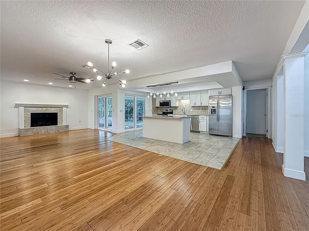 Empty room, Fireplace, Interior, Kitchen, Pendant Lights, Recessed Lighting, Stainless Steel Appliances, Wood Texture Flooring