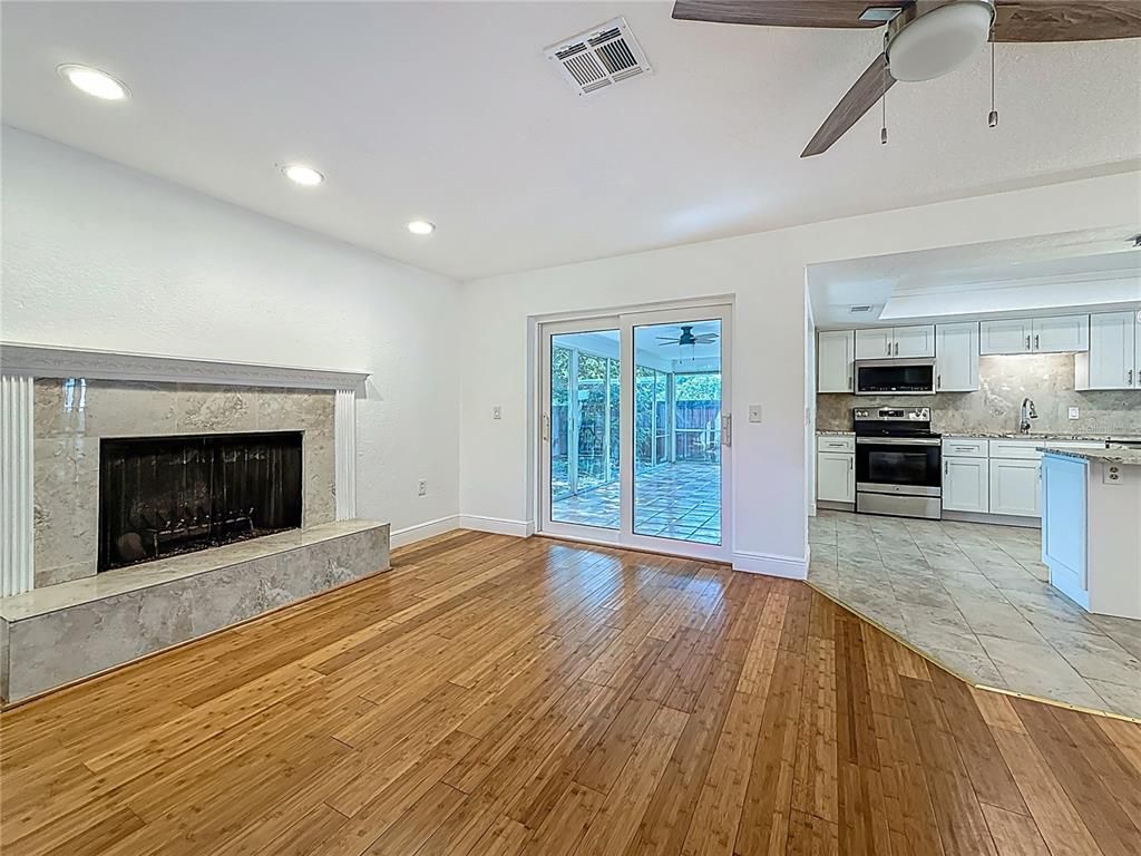 Empty room, Fireplace, Interior, Kitchen, Recessed Lighting, Stainless Steel Appliances, Wood Texture Flooring