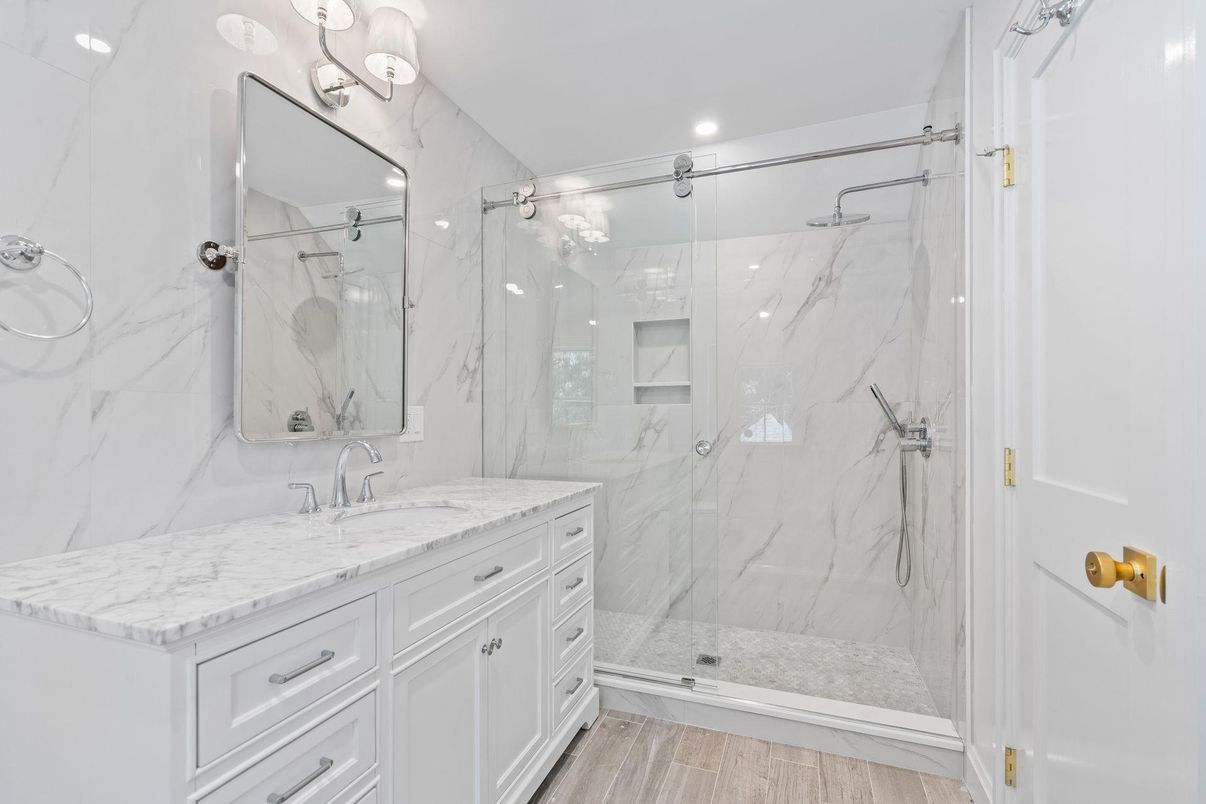 Bathroom, Dual Sink Vanities, Glass Shower, Interior, Marble Walls, Recessed Lighting, Wood Texture Flooring