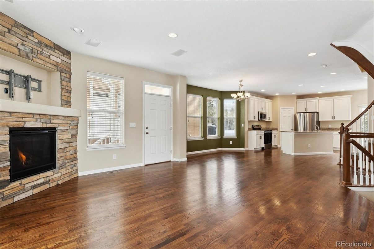 Chandelier, Empty room, Fireplace, Interior, Kitchen, Recessed Lighting, Stainless Steel Appliances, Wood Texture Flooring