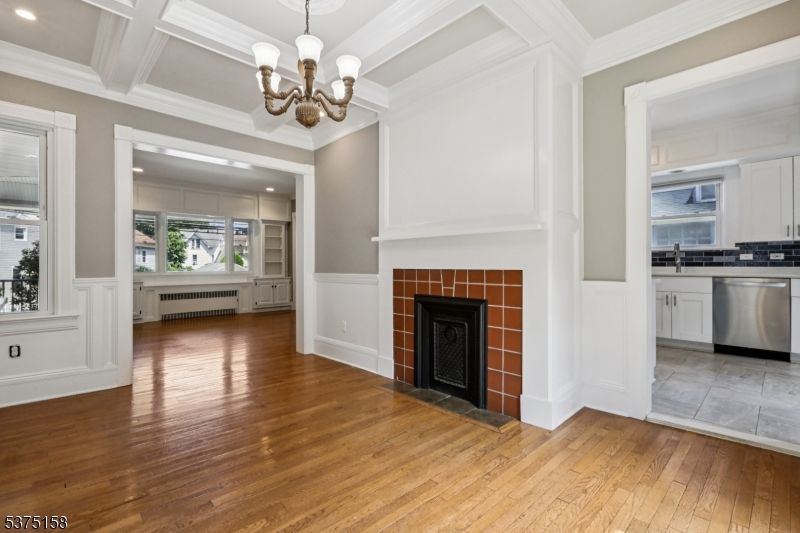 Chandelier, Empty room, Fireplace, Interior, Kitchen, Pendant Lights, Recessed Lighting, Stainless Steel Appliances, Wood Texture Flooring