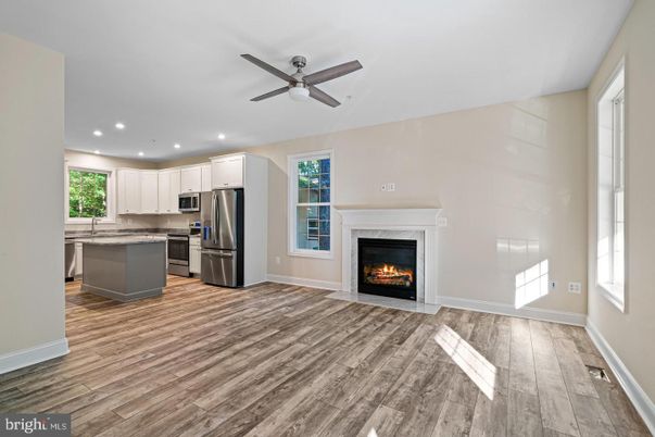 Empty room, Fireplace, Interior, Kitchen, Recessed Lighting, Stainless Steel Appliances, Wood Texture Flooring