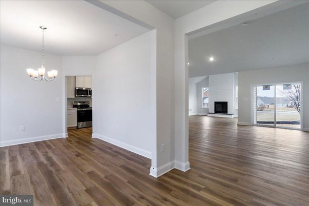 Chandelier, Empty room, Fireplace, Interior, Kitchen, Recessed Lighting, Stainless Steel Appliances, Wood Texture Flooring