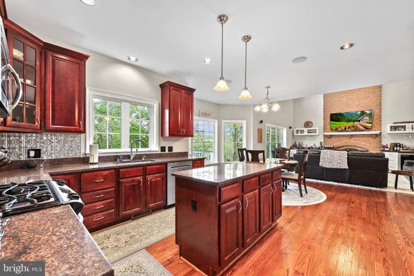 Chandelier, Dining room, Fireplace, Interior, Kitchen, Living room, Pendant Lights, Recessed Lighting, Stainless Steel Appliances, Stone Walls, Wood Texture Flooring