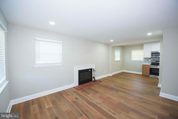 Empty room, Fireplace, Interior, Kitchen, Recessed Lighting, Stainless Steel Appliances, Wood Texture Flooring