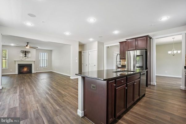 Chandelier, Empty room, Fireplace, Interior, Kitchen, Recessed Lighting, Stainless Steel Appliances, Wood Texture Flooring