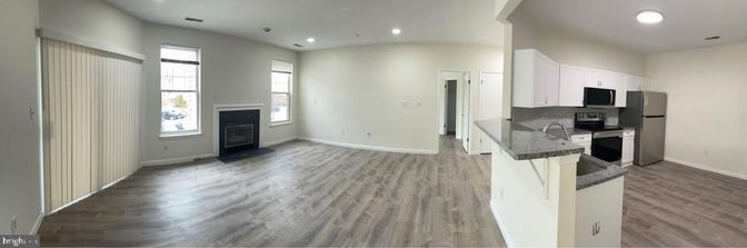 Empty room, Fireplace, Interior, Kitchen, Recessed Lighting, Stainless Steel Appliances, Wood Texture Flooring