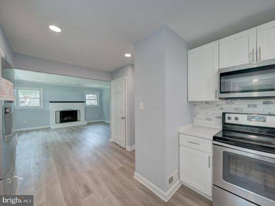 Empty room, Fireplace, Interior, Kitchen, Recessed Lighting, Stainless Steel Appliances, Wood Texture Flooring