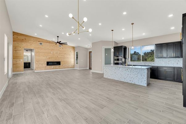 Empty room, Fireplace, Interior, Kitchen, Pendant Lights, Recessed Lighting, Stainless Steel Appliances, Stone Walls, Wood Texture Flooring, Wooden Walls