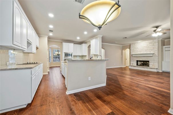 Empty room, Fireplace, Interior, Kitchen, Recessed Lighting, Stainless Steel Appliances, Stone Walls, Wood Texture Flooring