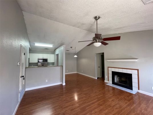 Empty room, Fireplace, Interior, Kitchen, Pendant Lights, Stainless Steel Appliances, Wood Texture Flooring