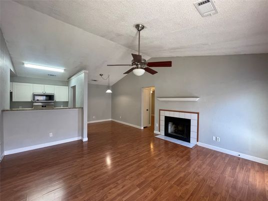 Empty room, Fireplace, Interior, Kitchen, Pendant Lights, Stainless Steel Appliances, Wood Texture Flooring