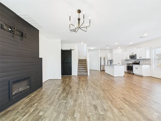 Chandelier, Empty room, Fireplace, Interior, Kitchen, Pendant Lights, Recessed Lighting, Stainless Steel Appliances, Wood Texture Flooring