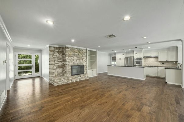 Empty room, Fireplace, Interior, Kitchen, Recessed Lighting, Stainless Steel Appliances, Stone Walls, Wood Texture Flooring
