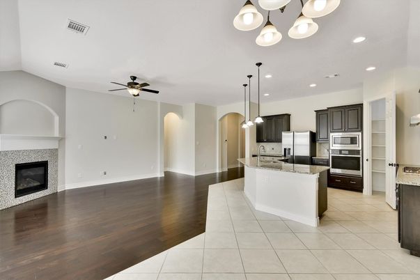 Empty room, Fireplace, Interior, Kitchen, Pendant Lights, Recessed Lighting, Stainless Steel Appliances, Wood Texture Flooring