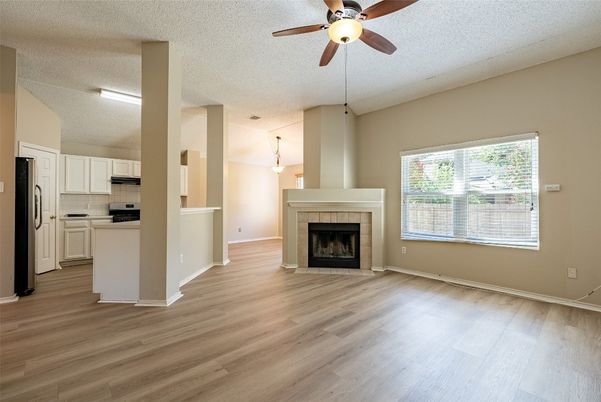 Empty room, Fireplace, Interior, Kitchen, Pendant Lights, Stainless Steel Appliances, Wood Texture Flooring