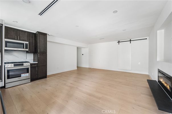 Empty room, Fireplace, Interior, Kitchen, Recessed Lighting, Stainless Steel Appliances, Wood Texture Flooring